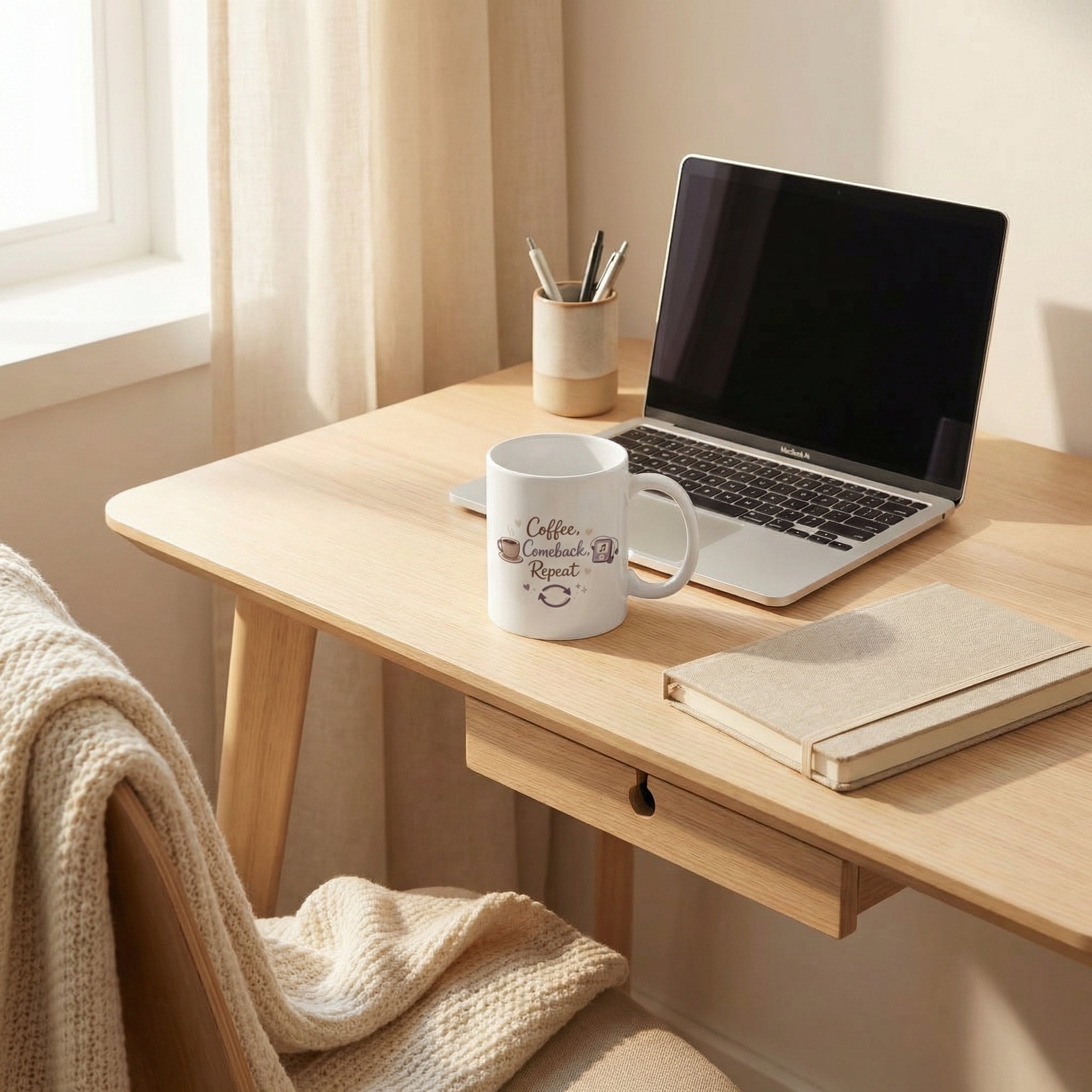 Home office setup with a laptop, mug, and notebook on a wooden desk.