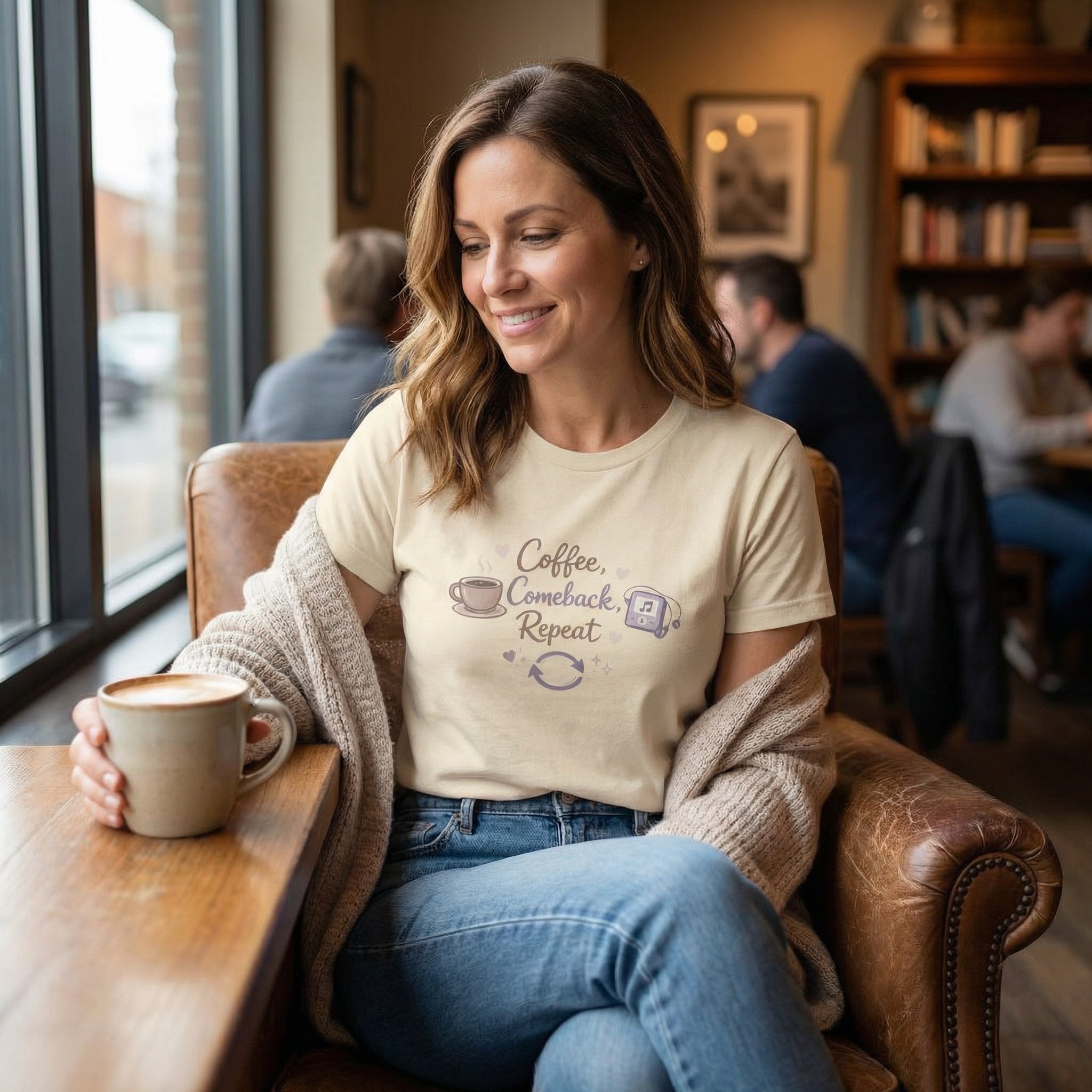 Woman sitting in a cozy cafe, holding a coffee cup and wearing a t-shirt with a coffee-themed design.