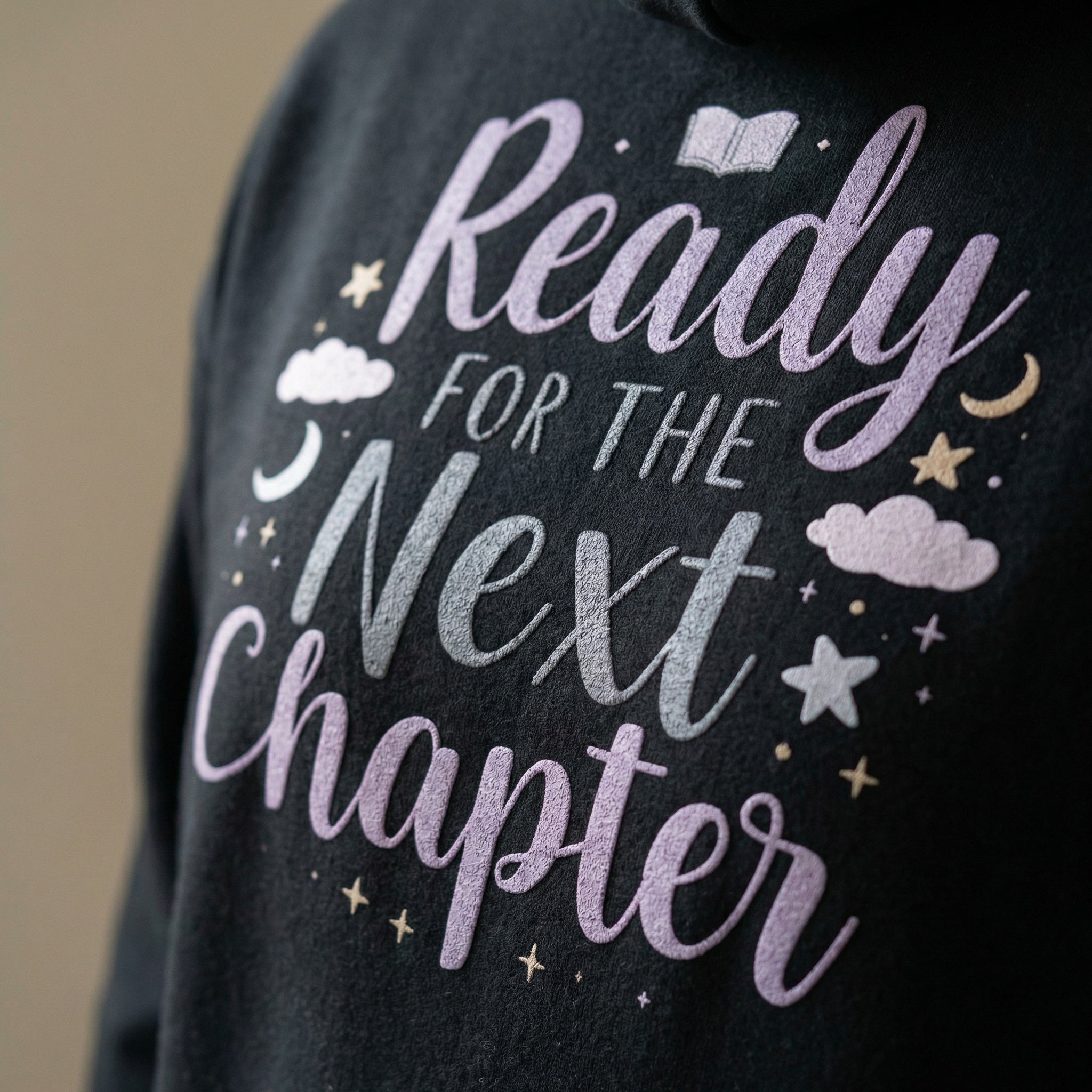 Black shirt with 'Ready for the Next Chapter' text and decorative elements on a beige background