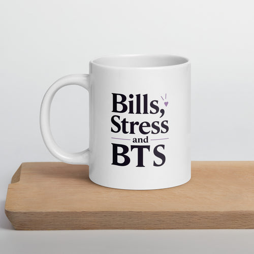 White mug with 'Bills, Stress and BTS' text on a wooden surface