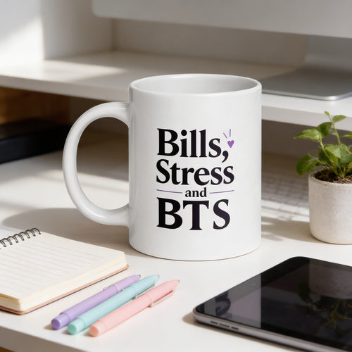 White mug with 'Bills, Stress and BTS' text on a desk with stationery items.